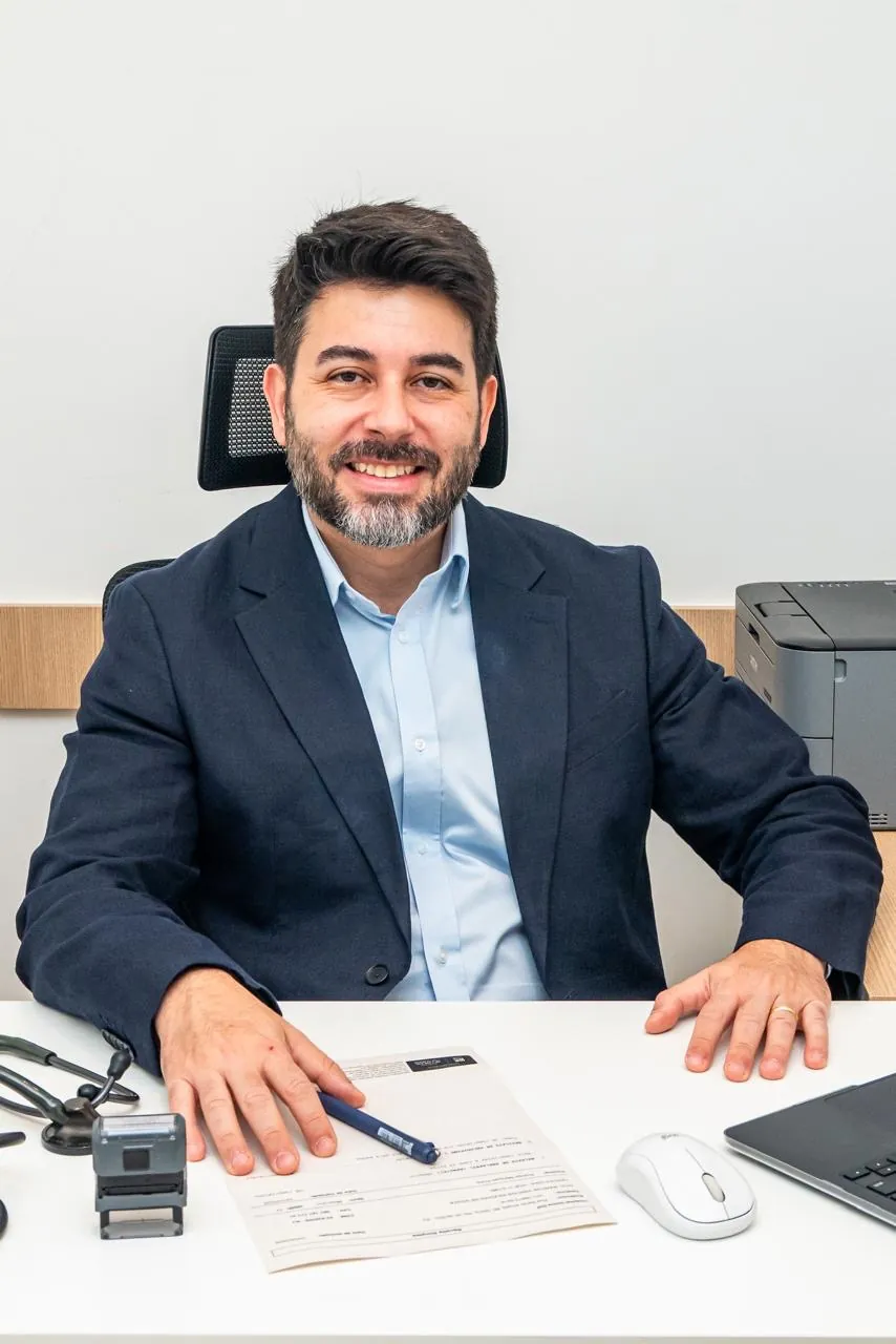 Dr. Marcus Vinicius Iglesias à mesa do consultório em Copacabana